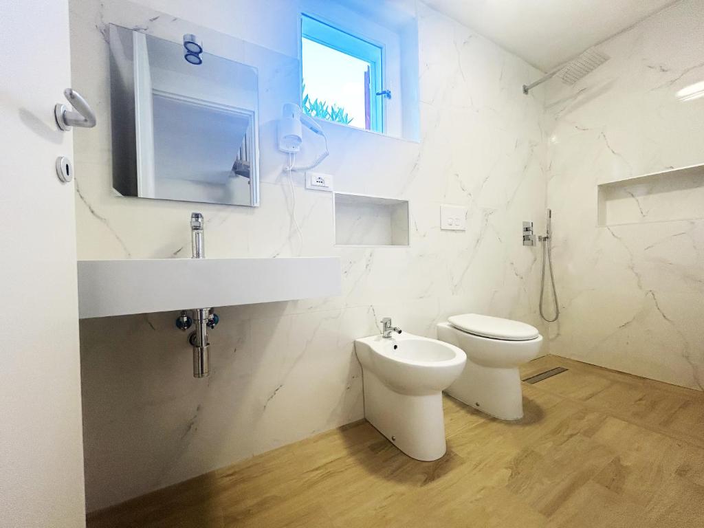 une salle de bain blanche avec toilettes et lavabo dans l'établissement Case Vacanze a Rossano, à Rossano