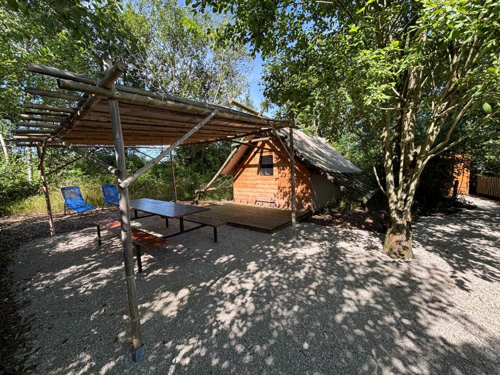 une cabane en rondins avec une table de pique-nique et un arbre dans l'établissement Camp du Père Castor, à Simard