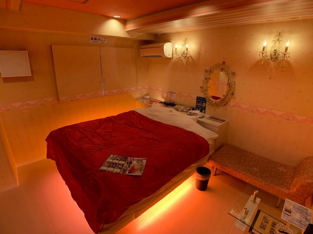 une petite chambre avec un lit rouge et un banc dans l'établissement 愛愛賓館 Adult Only, à Wada