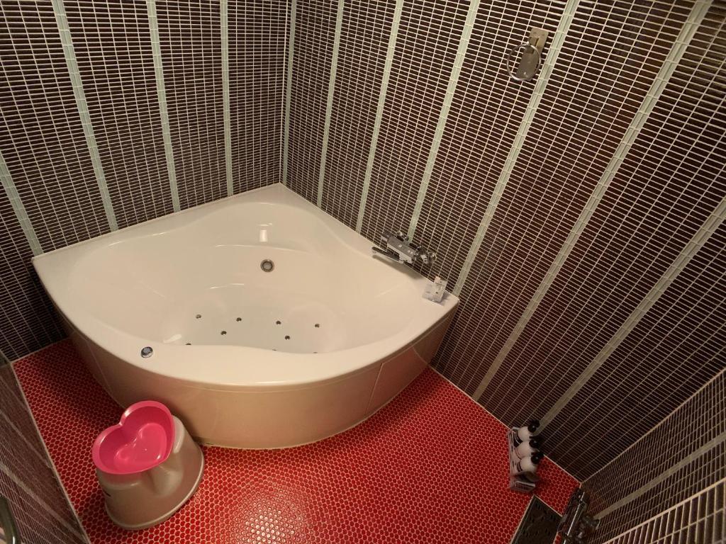La salle de bains est pourvue d'une baignoire et d'un sol rouge. dans l'établissement 愛愛賓館 Adult Only, à Wada