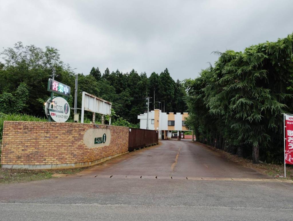 une rue vide avec un mur en briques et des arbres dans l'établissement HOTEL i, à Takahata