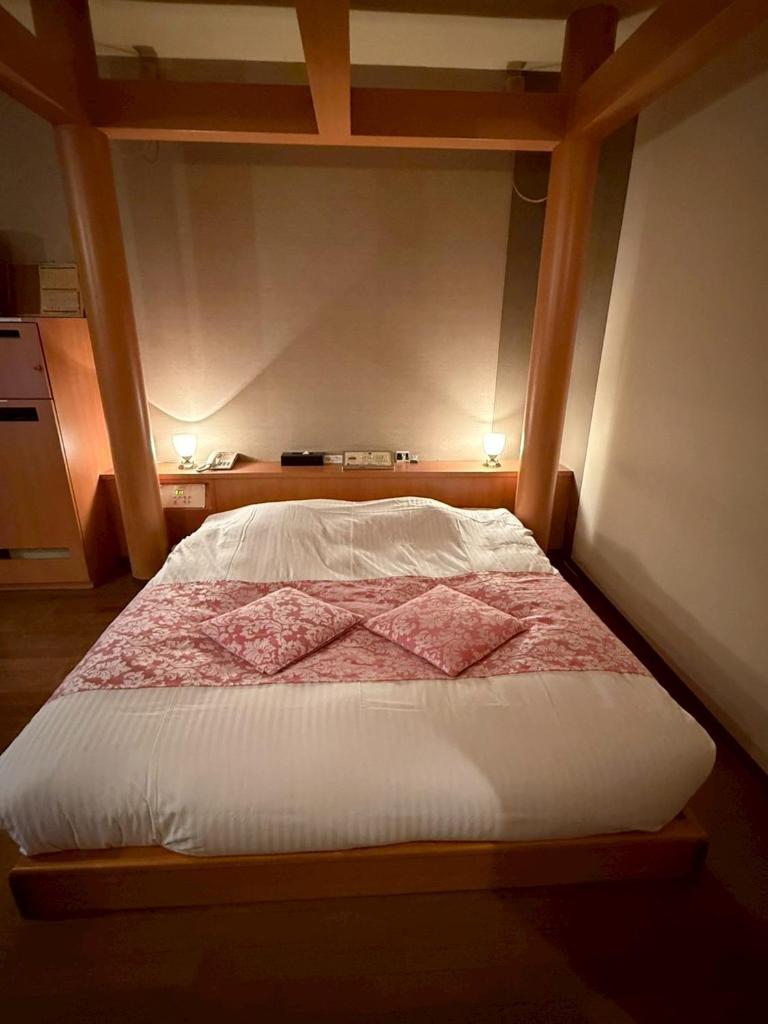 un lit dans une chambre avec un cadre en bois dans l'établissement HOTEL i, à Takahata