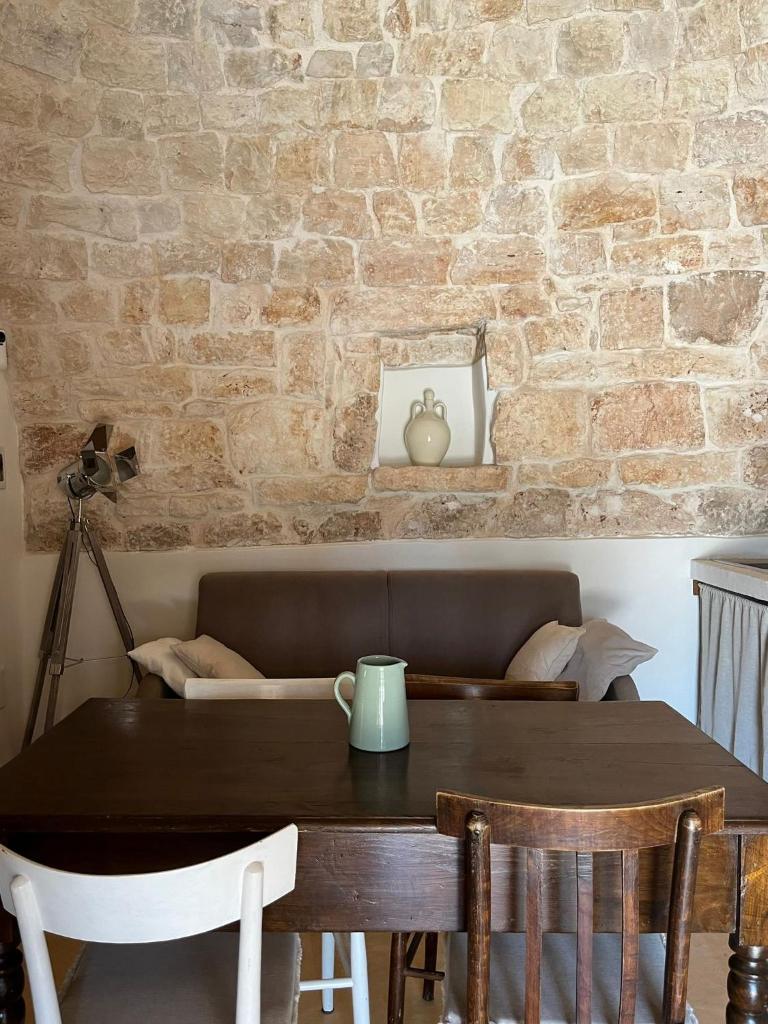 une table à manger avec des chaises et un mur en briques dans l'établissement Trullo Terracielo, à Ceglie Messapica 20 autres photos