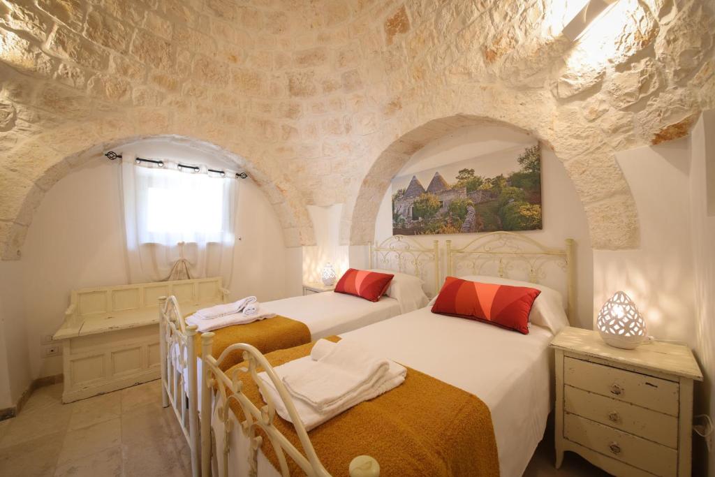 une chambre avec deux lits et un mur en pierre dans l'établissement Trulli del Carrubo by Apulia Hospitality, à Locorotondo