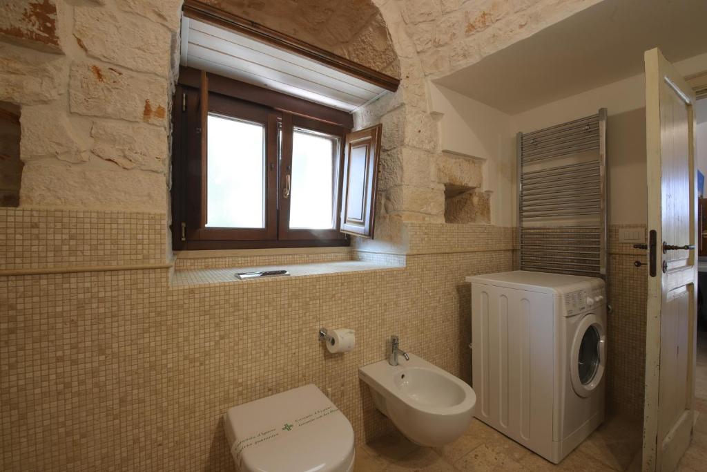 une salle de bain avec des toilettes blanches et un lavabo dans l'établissement Trulli del Carrubo by Apulia Hospitality, à Locorotondo 32 autres photos