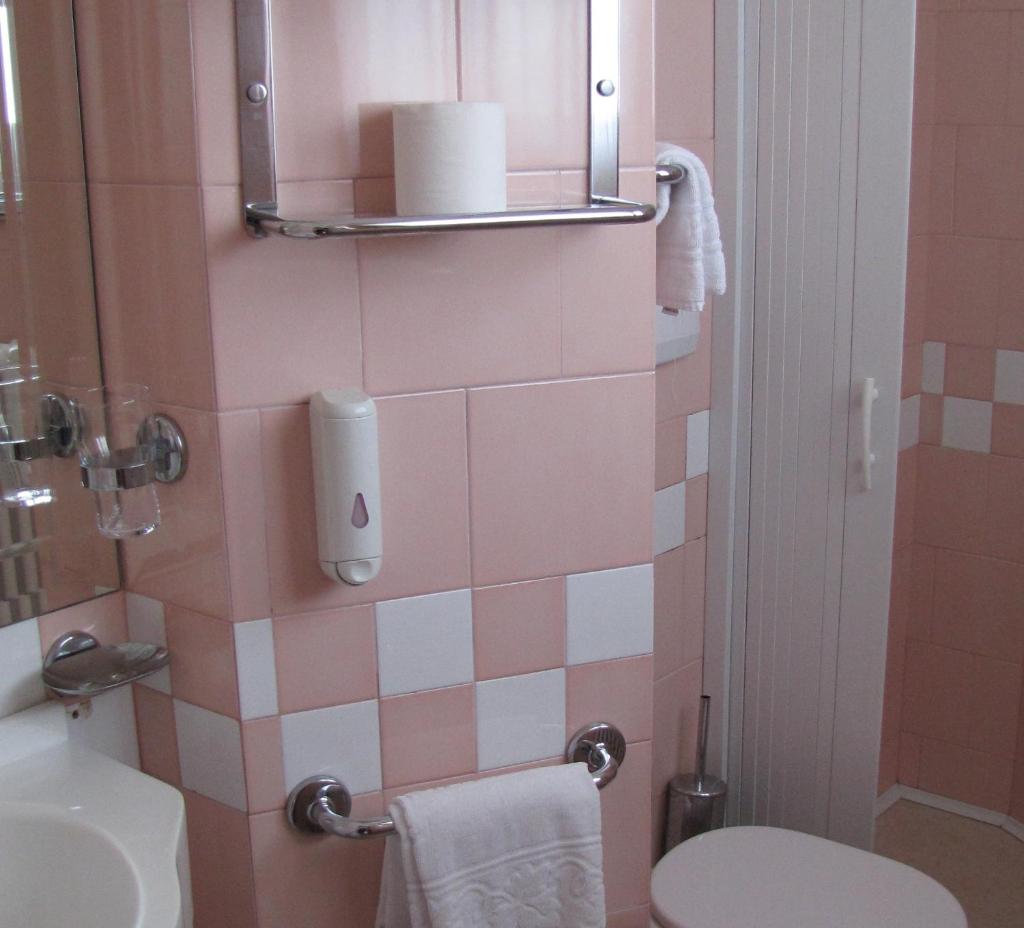 une salle de bains rose avec toilettes et lavabo. dans l'établissement Hotel Lanterna, à Porto San Giorgio