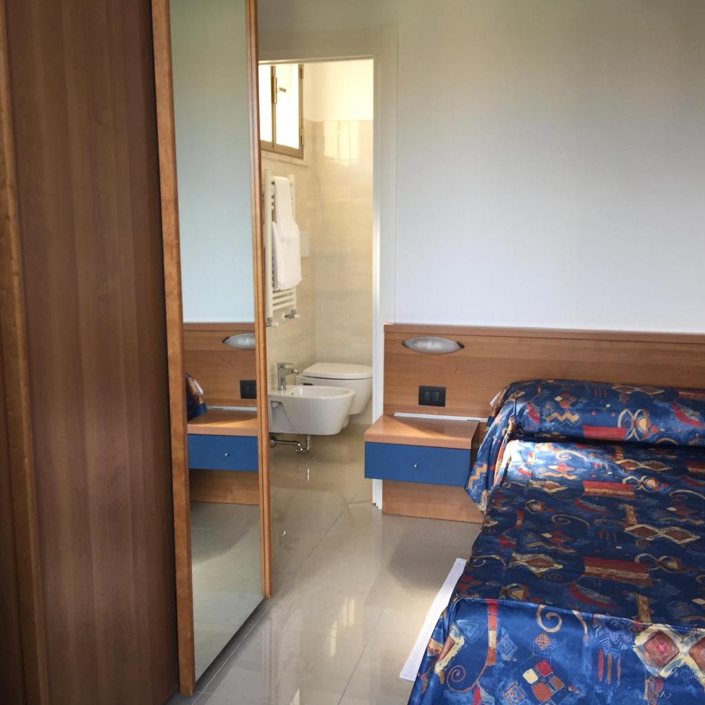 une chambre avec un lit et une salle de bains avec un miroir dans l'établissement Hotel Athena, à Pesaro