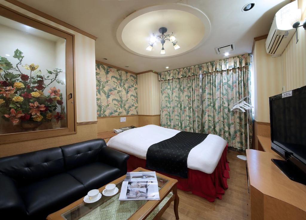 une chambre d'hôtel avec un lit et un canapé dans l'établissement Hotel Mio Resort ( Adult Only), à Yokkaichi