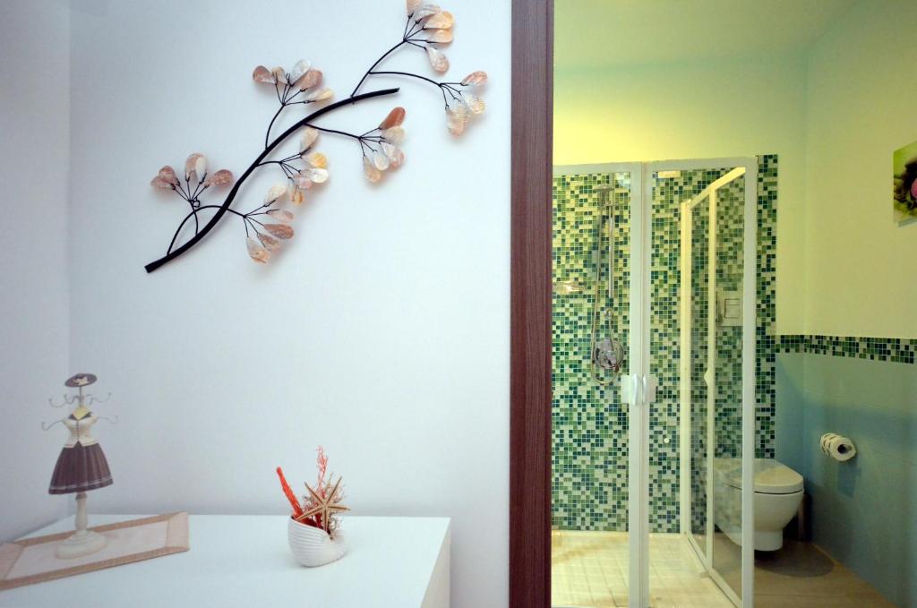 une salle de bain avec des toilettes et une branche avec des fleurs sur le mur dans l'établissement Ciuri Di Mari, à San Vito Lo Capo