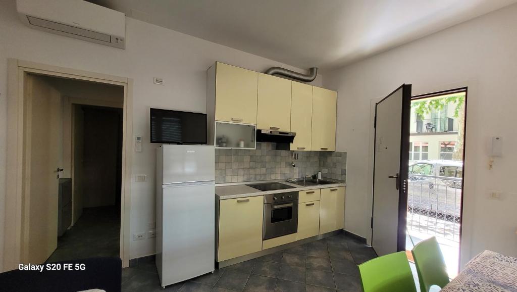 une cuisine avec des appareils électroménagers blancs et des armoires jaunes dans l'établissement Residence Désirée, à Rimini