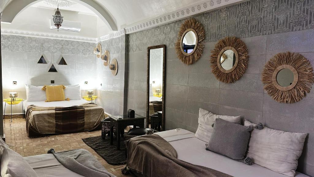 - une chambre avec 2 lits et des miroirs sur le mur dans l'établissement RIAD MAMAHOUSE, à Marrakech