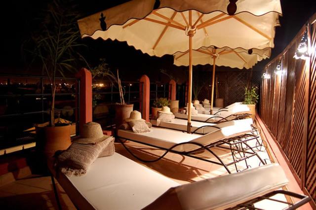 - un ensemble de chaises longues avec parasols sur la terrasse dans l'établissement Riad D'Airain, à Marrakech