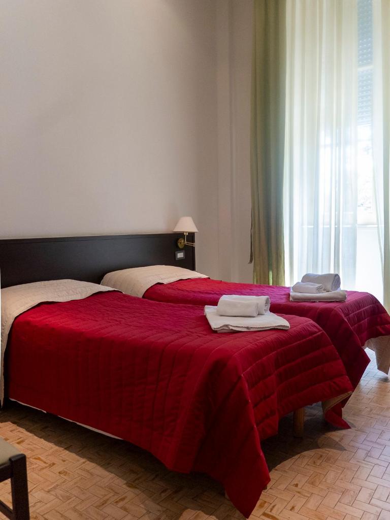 - une chambre avec 2 lits et des couvertures rouges dans l'établissement Sacro Cuore Hotel, à Marina di Massa