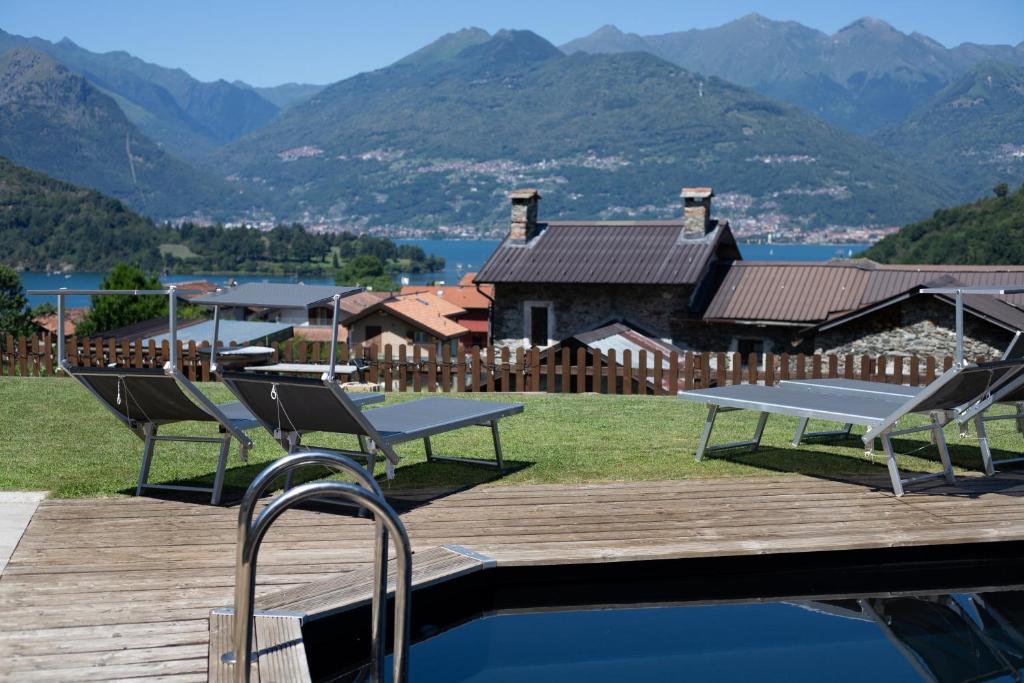 une piscine avec des chaises, une maison et des montagnes dans l'établissement Villa Vento, à Colico