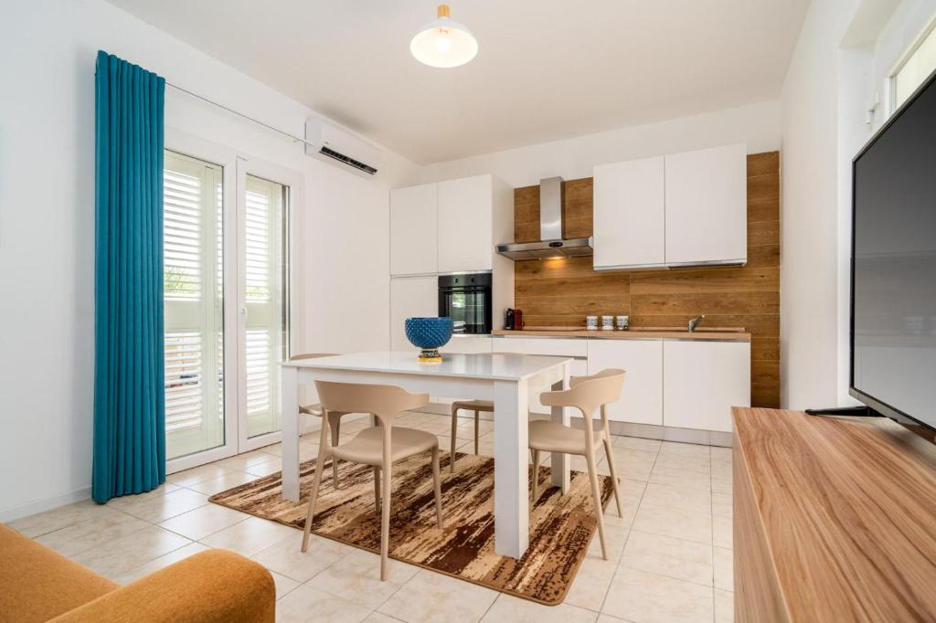 une cuisine et une salle à manger avec une table et des chaises blanches dans l'établissement Villademar lunarossa, à Marzamemi
