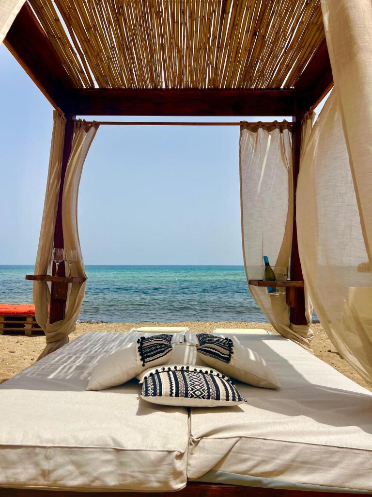 - un lit sur la plage avec l'océan en arrière-plan dans l'établissement Villademar lunarossa, à Marzamemi
