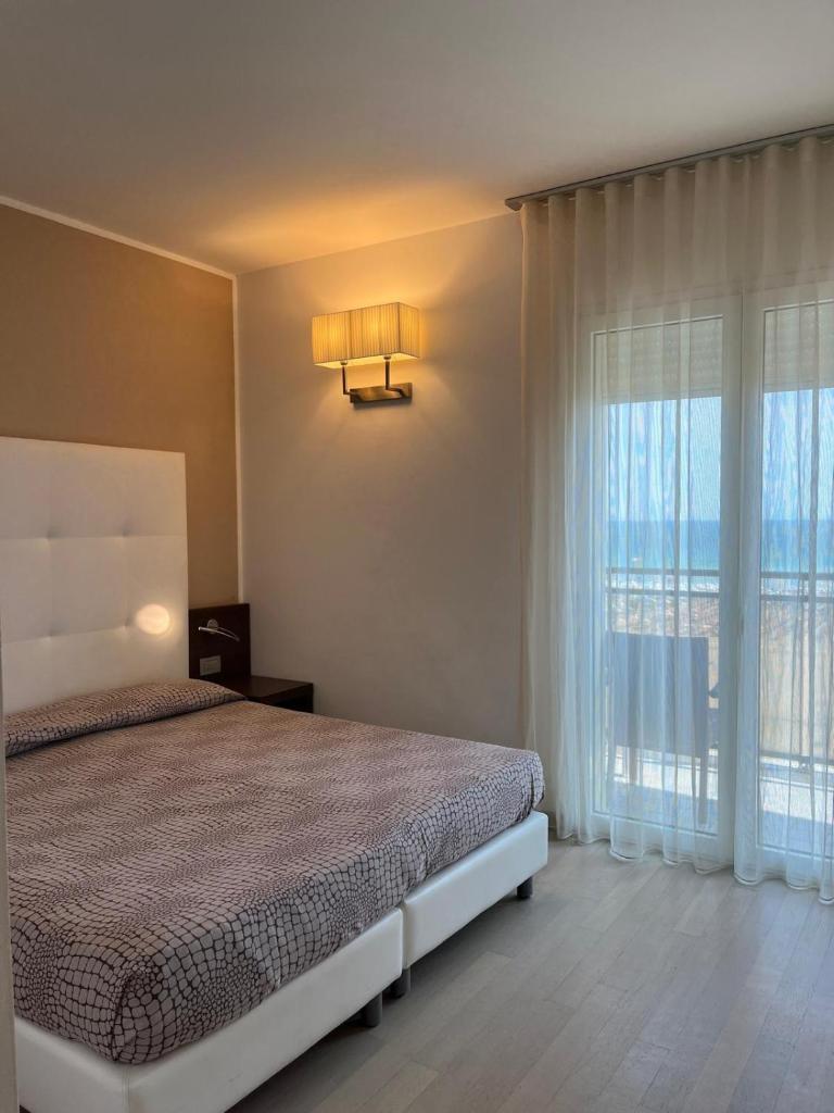 une chambre avec un lit et une grande fenêtre dans l'établissement Hotel Italy, à Bibione 59 autres photos