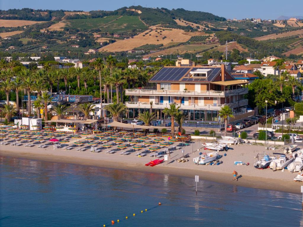 une plage avec des chaises et des parasols et un complexe hôtelier dans l'établissement Hotel Graziella, à Martinsicuro