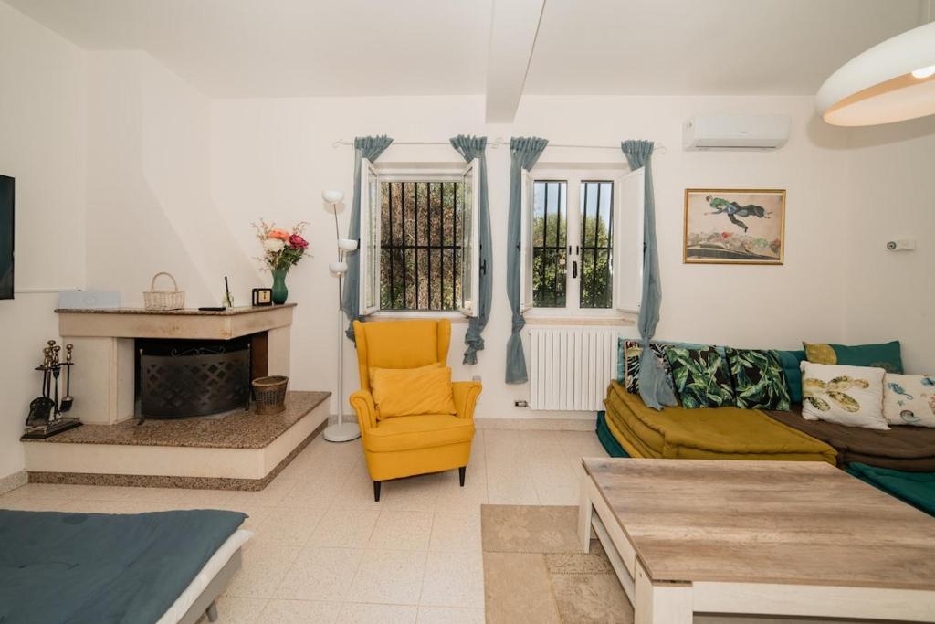 un salon avec une chaise jaune et un canapé dans l'établissement Villa Trullo Cantaluna - Esclusiva villa con trullo e piscina privata, à Ceglie Messapica