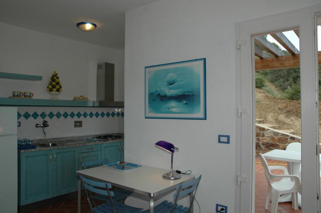 une cuisine avec des placards bleus et une table munie d'une lampe. dans l'établissement Residence Cala dei Peducelli, à Capoliveri