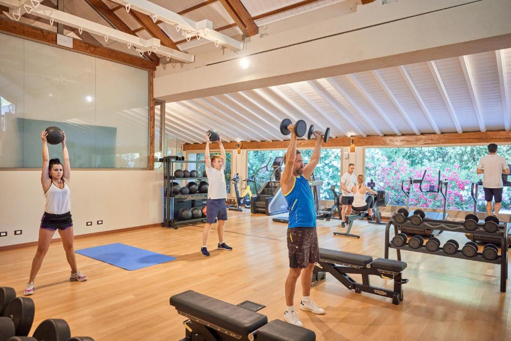 un groupe de personnes dans une salle de sport levant des poids dans l'établissement Forte Village Resort - Villa Del Parco & Spa, à Santa Margherita di Pula
