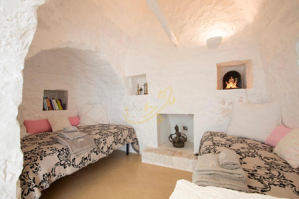Cette chambre comprend 2 lits et une cheminée. dans l'établissement TD Trulli Vittoriani Charme and Pure Nature w pool, à Ostuni