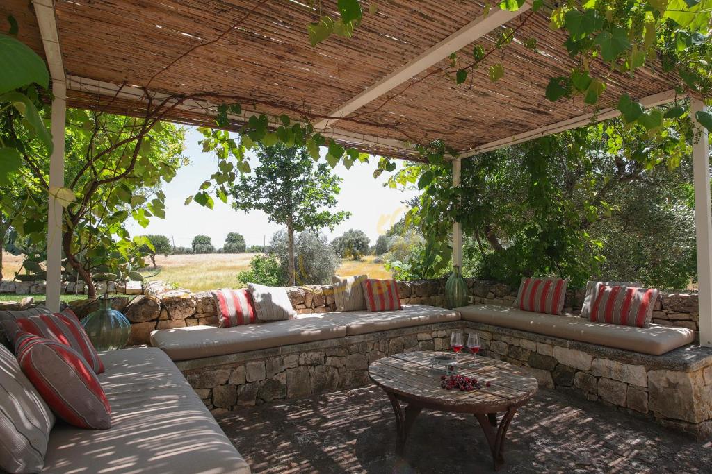 une terrasse avec un canapé et une table sous une pergola dans l'établissement TD Trulli Vittoriani Charme and Pure Nature w pool, à Ostuni