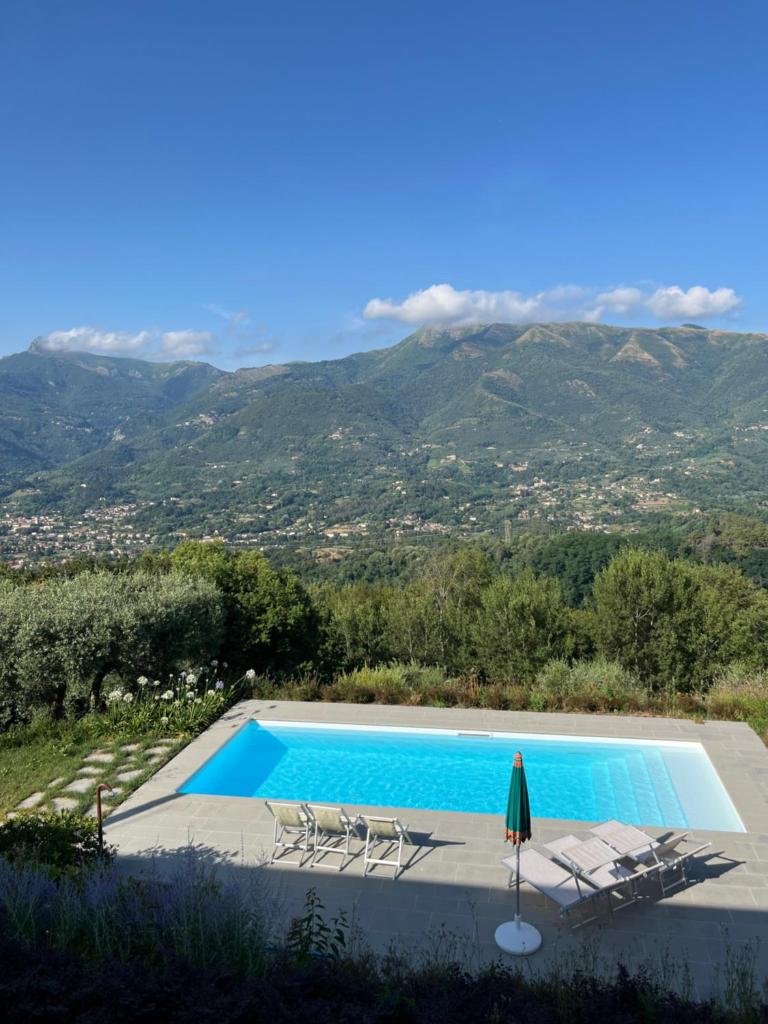 une piscine avec des chaises et une montagne en arrière-plan dans l'établissement Villa Prana by Nicola Real Estate, à Corsanico-Bargecchia