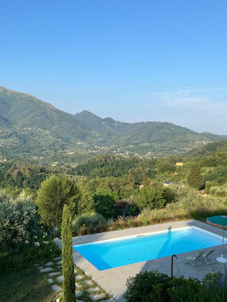 une piscine avec des montagnes en arrière-plan dans l'établissement Villa Prana by Nicola Real Estate, à Corsanico-Bargecchia