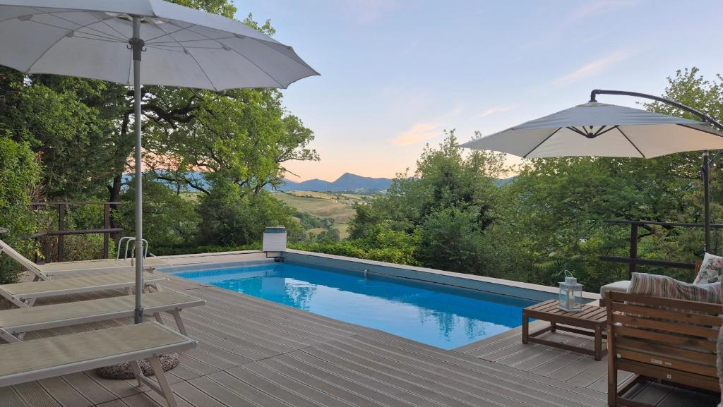 - une piscine avec un parasol, des chaises et une table dans l'établissement villa la chiesetta - private pool - Borgo Canapegna, à Fabriano