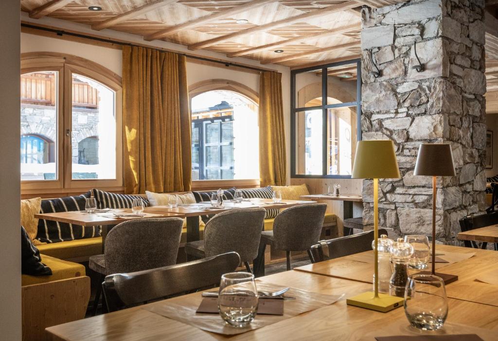 un restaurant avec des tables et des chaises en bois et des fenêtres dans l'établissement Chalet Hôtelier LES EQUINOXES - VAL D'ISERE, à La Daille