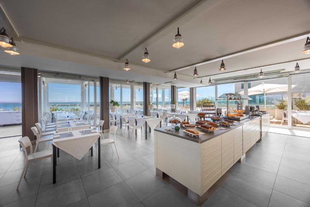 un restaurant avec des tables, des chaises et des fenêtres dans l'établissement Nautilus Family Hotel, à Pesaro