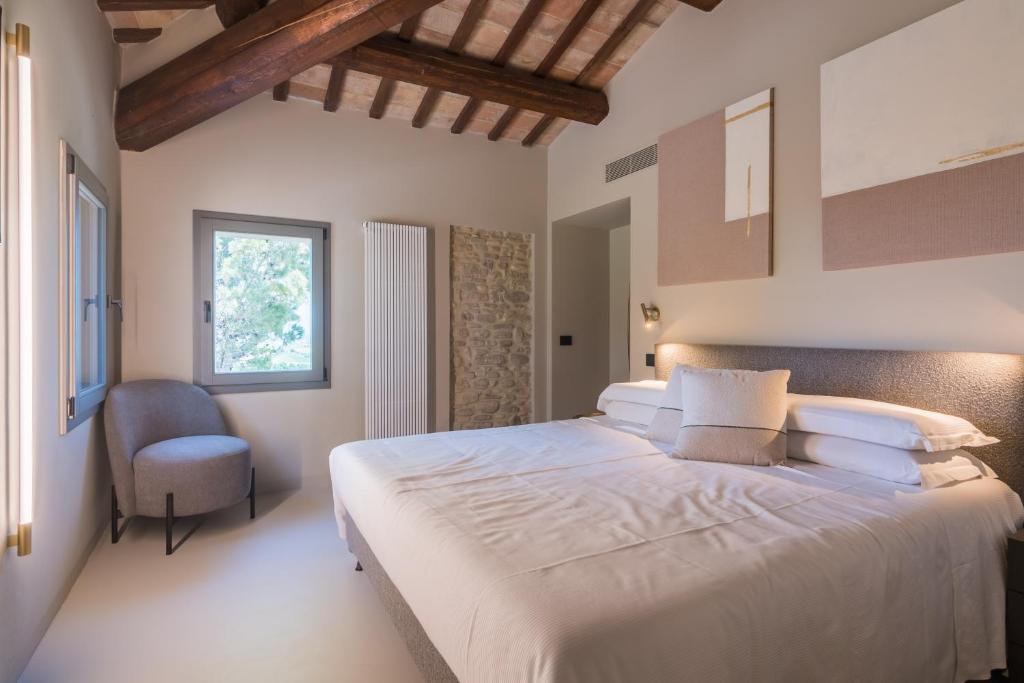 une chambre avec un grand lit blanc et une chaise dans l'établissement Villa Maracci, à San Savino 121 autres photos