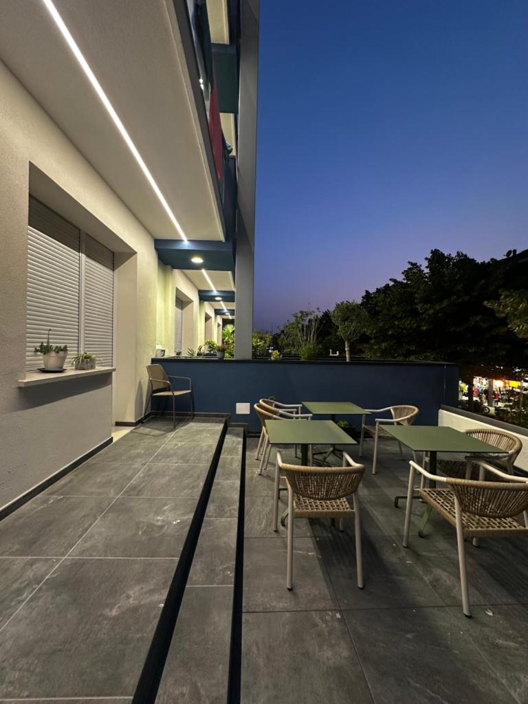 un patio avec des tables et des chaises sur un bâtiment dans l'établissement Lilium Maris Hotel, à Bibione