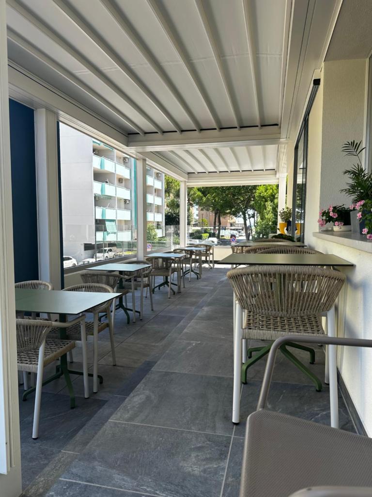 une rangée de tables et de chaises sur une terrasse dans l'établissement Lilium Maris Hotel, à Bibione