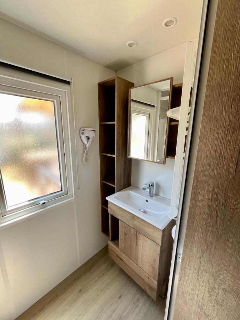 une salle de bain avec un lavabo et une fenêtre dans l'établissement Bontempo Village camping 4 étoiles, à Piriac-sur-Mer
