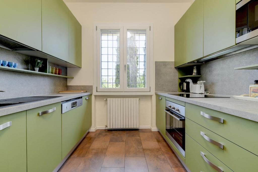 une grande cuisine avec des placards verts et une fenêtre dans l'établissement Villa Stefano by Garda FeWo, à Soiano del Lago