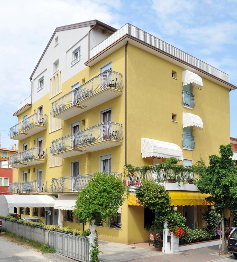 - un bâtiment jaune avec balcon dans une rue dans l'établissement Hotel Helga, à Caorle