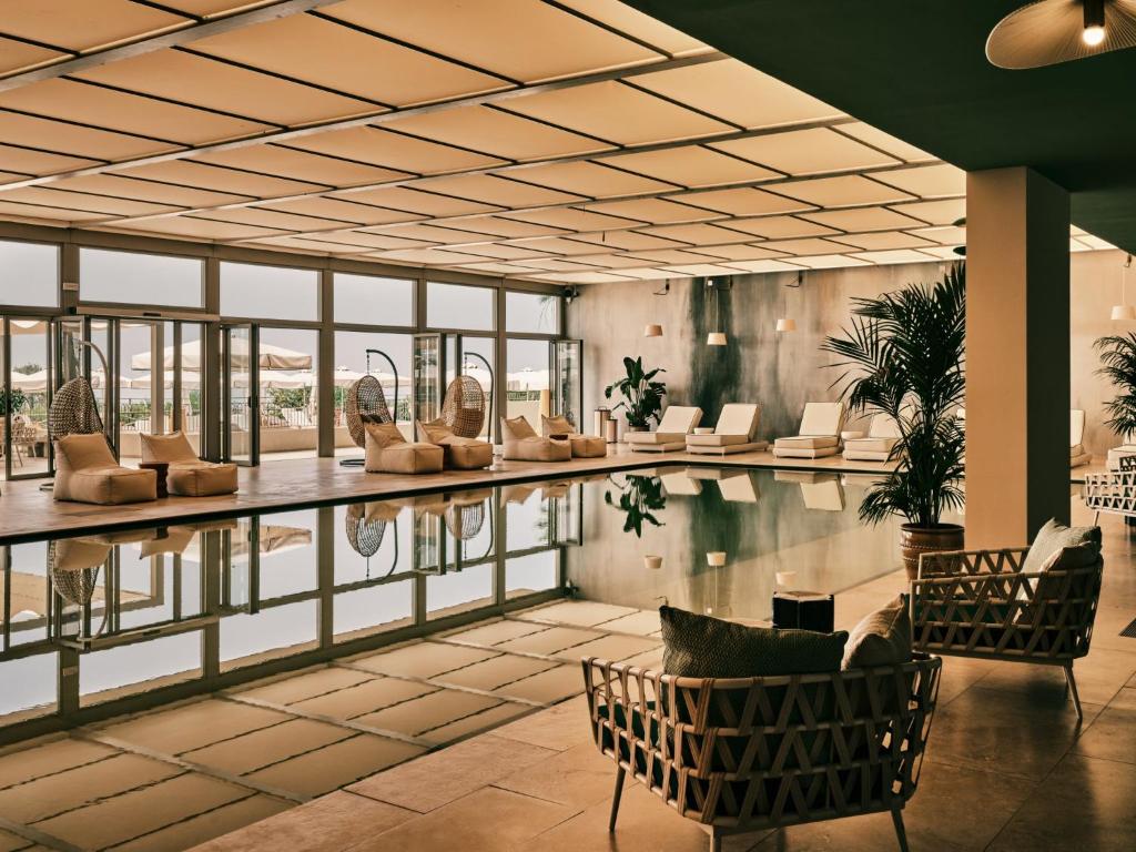 - une piscine dans un bâtiment avec des chaises et des tables dans l'établissement Mangia's Torre Del Barone Resort & SPA, à Sciacca