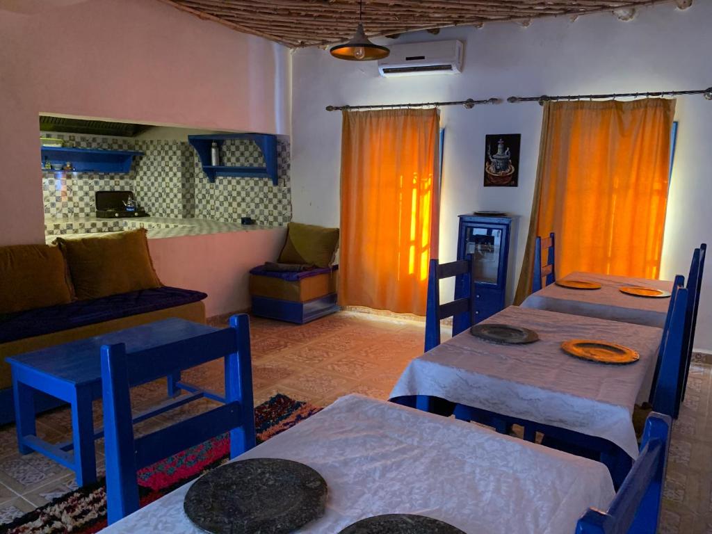 une pièce avec deux tables et deux chaises avec des rideaux orange dans l'établissement Chez Youssef, à Merzouga