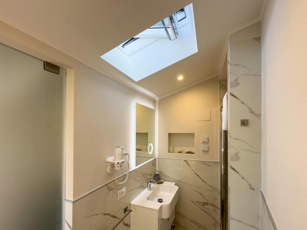 La salle de bains est pourvue d'un lavabo et d'une lucarne. dans l'établissement Hotel Biagi & Residence, à Lido di Camaiore
