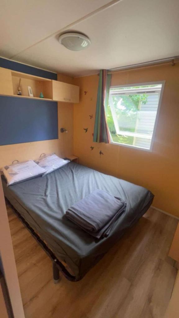 un petit lit dans une chambre avec une fenêtre dans l'établissement Camping Tohapi Coeur de Vendée, à La Boissière-de-Montaigu