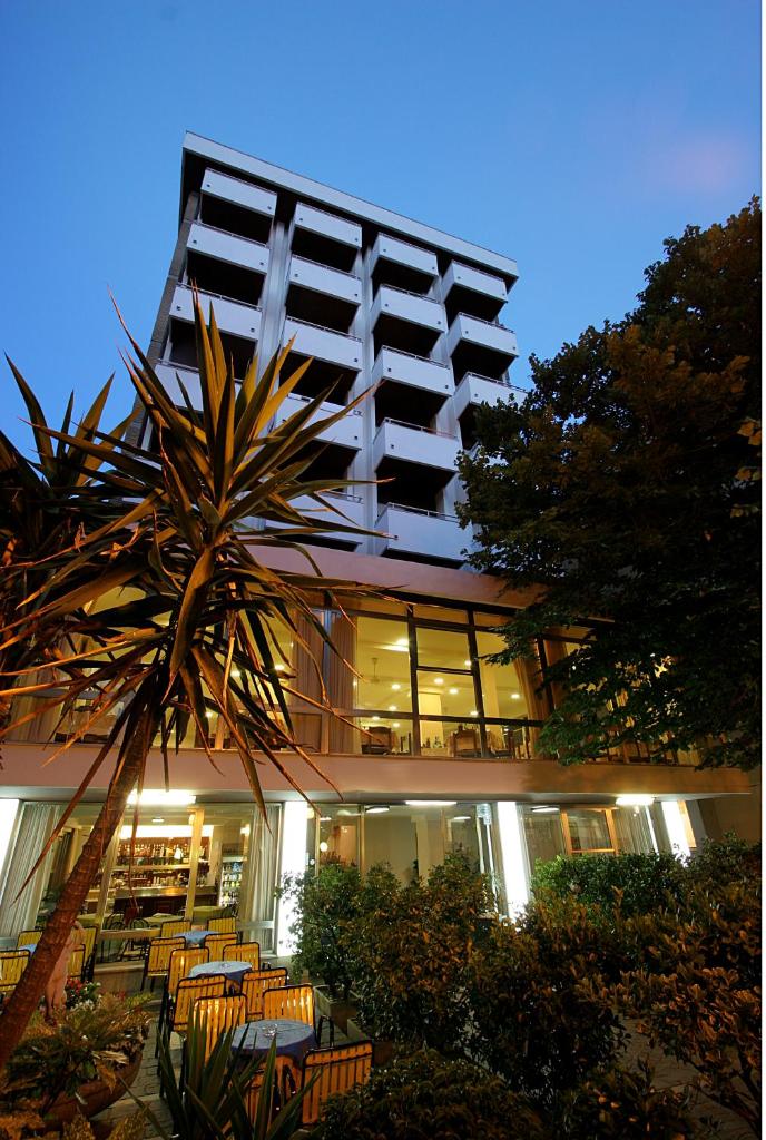 un bâtiment avec des chaises et un palmier devant dans l'établissement Mon Hotel, à Misano Adriatico