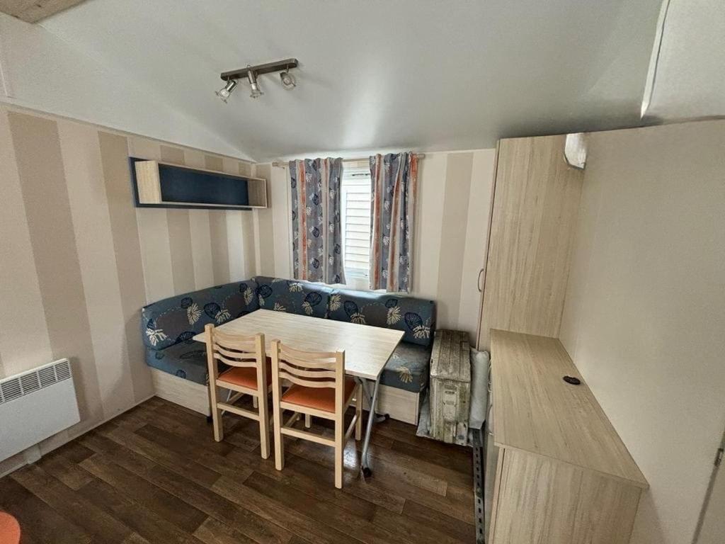 une salle à manger avec une table et un canapé bleu dans l'établissement Mobil home - Rieumontagne Particulier, à Nages