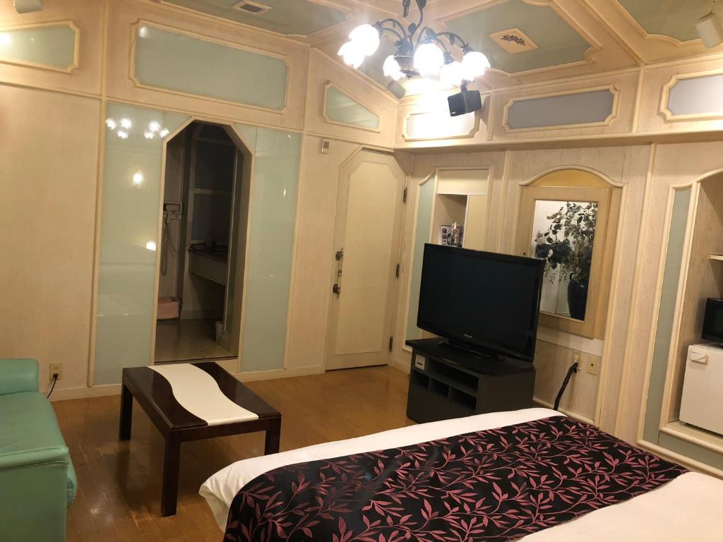 - une chambre avec une télévision à écran plat et un lit dans l'établissement ホテルハンズ, à Ginan