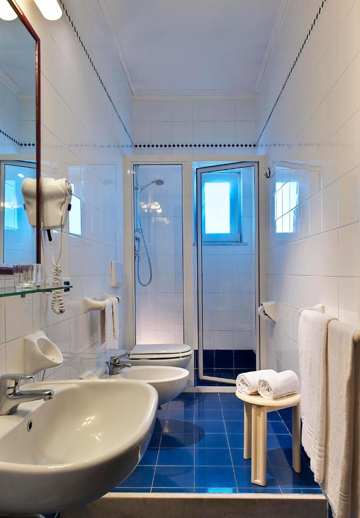 une salle de bain blanche avec deux lavabos et une douche dans l'établissement Parco Aurora Terme, à Ischia