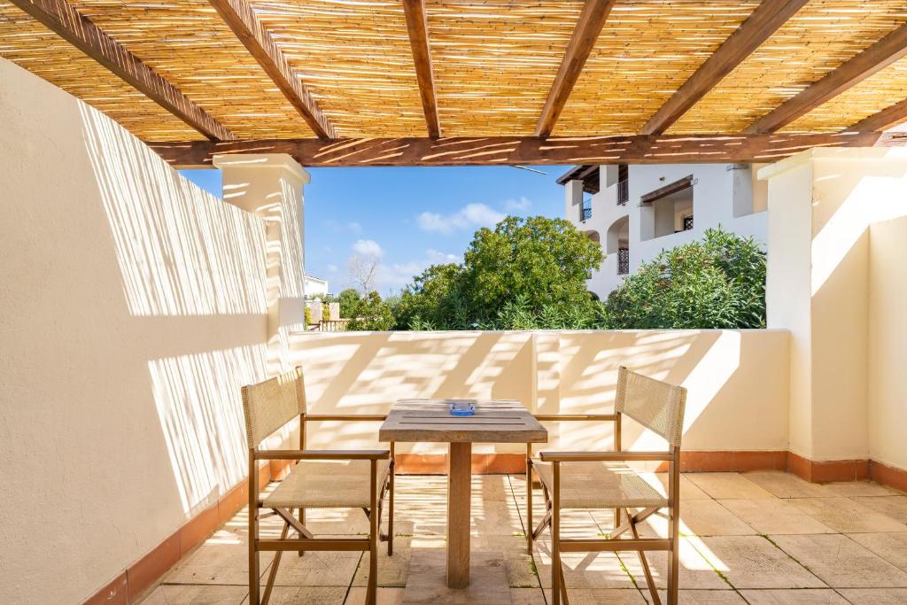 une table et des chaises sur une terrasse avec une pergola en bois dans l'établissement Hotel La Caletta Village, à La Caletta