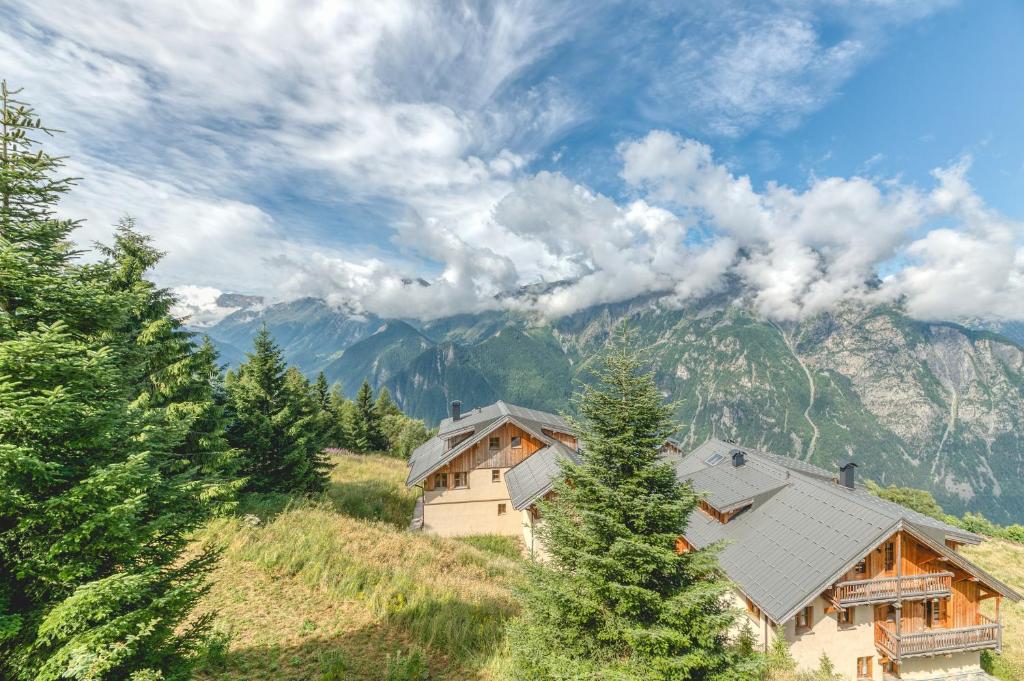 une maison sur une colline avec des montagnes en arrière-plan dans l'établissement Meije 4 Chaleureux Appt Proche, à Villard-Reculas