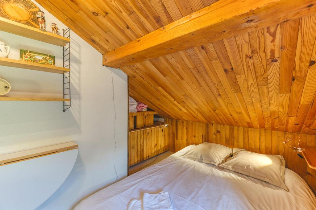 un lit dans une chambre avec un plafond en bois dans l'établissement Meije 4 Chaleureux Appt Proche, à Villard-Reculas