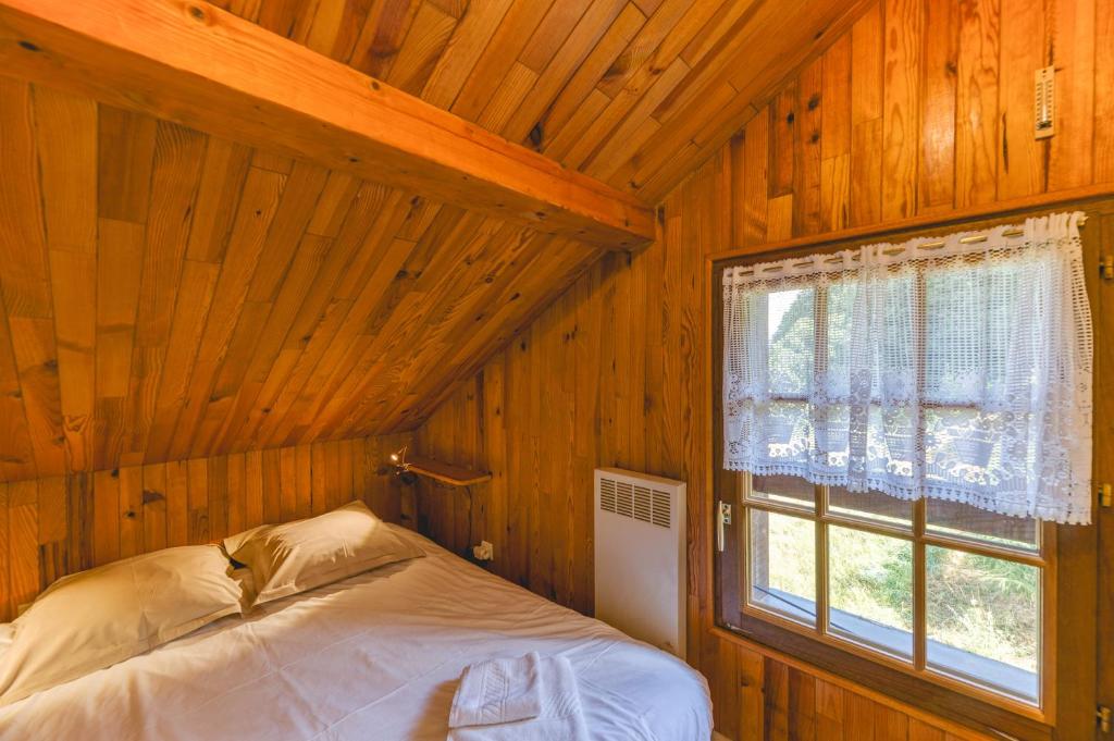 Ce lit se trouve dans une chambre en bois dotée d'une fenêtre. dans l'établissement Meije 4 Chaleureux Appt Proche, à Villard-Reculas